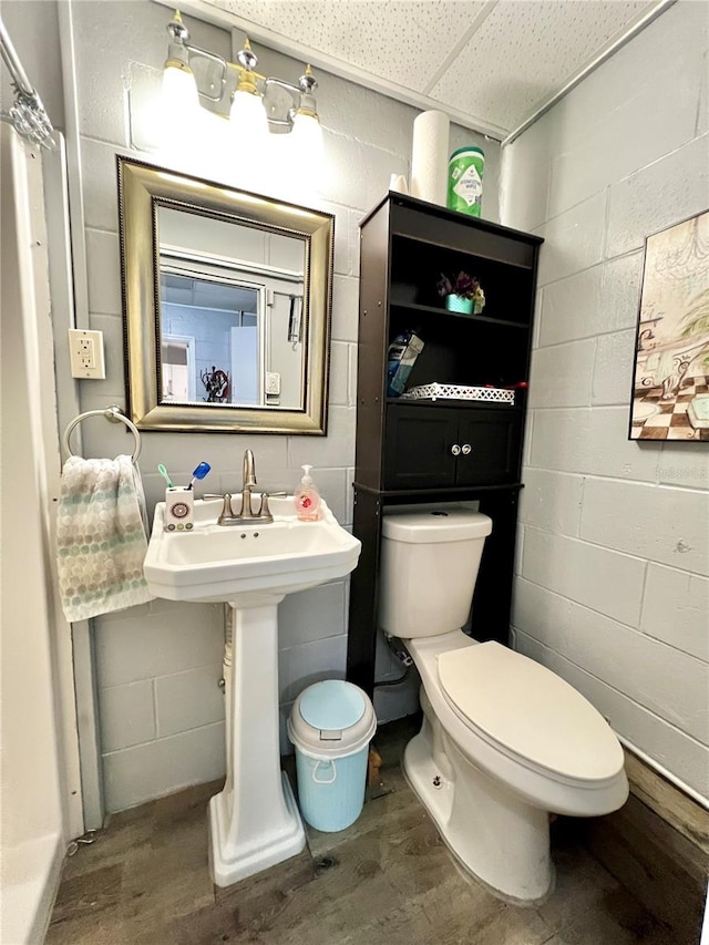 bathroom with toilet, a drop ceiling, and hardwood / wood-style floors