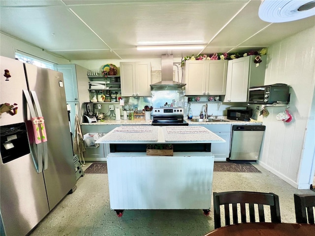 kitchen with wall chimney range hood, sink, a kitchen island, white cabinetry, and stainless steel appliances