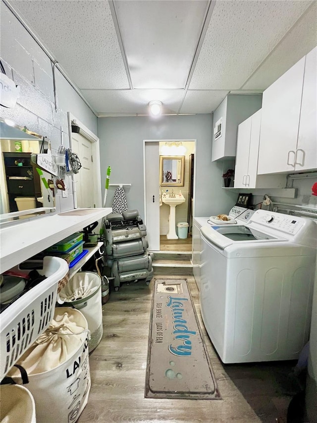 laundry room featuring separate washer and dryer, cabinets, light wood-type flooring, and sink