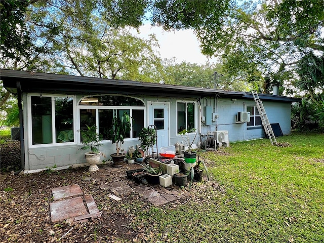 back of house with a wall mounted air conditioner and a lawn