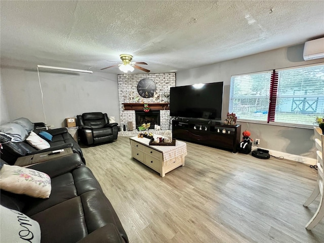 living room with ceiling fan, a textured ceiling, light hardwood / wood-style flooring, and a fireplace