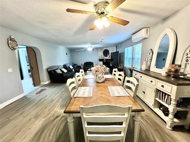 dining room with ceiling fan, hardwood / wood-style flooring, a wall mounted AC, and a textured ceiling