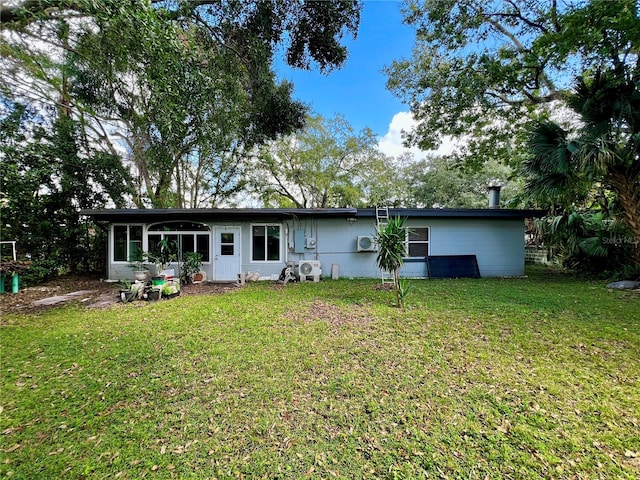 back of property featuring a sunroom and a lawn