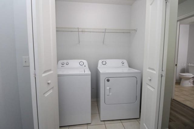 clothes washing area with washer and dryer and light tile patterned floors