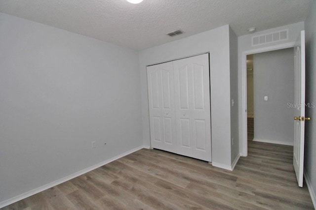 unfurnished bedroom featuring a closet, light hardwood / wood-style floors, and a textured ceiling