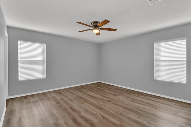 spare room featuring a textured ceiling, light wood-type flooring, and ceiling fan