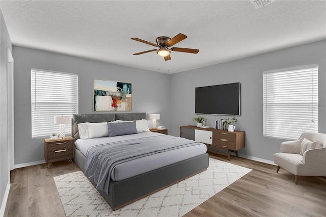 bedroom featuring ceiling fan, a textured ceiling, and light wood-type flooring