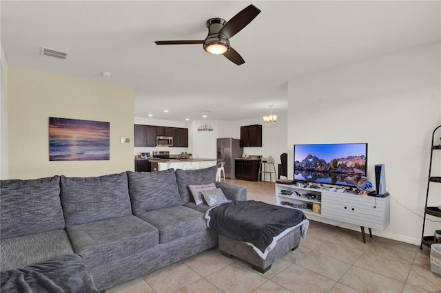 living room featuring light tile patterned floors and ceiling fan with notable chandelier