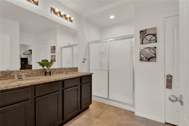 bathroom with a shower with door, vanity, and tile patterned floors