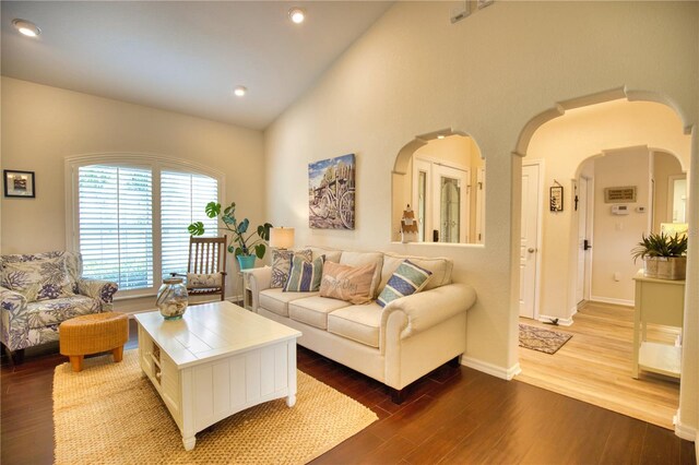 living room with high vaulted ceiling and dark hardwood / wood-style flooring