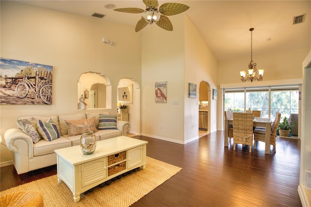 living room with dark wood-type flooring, ceiling fan with notable chandelier, and high vaulted ceiling