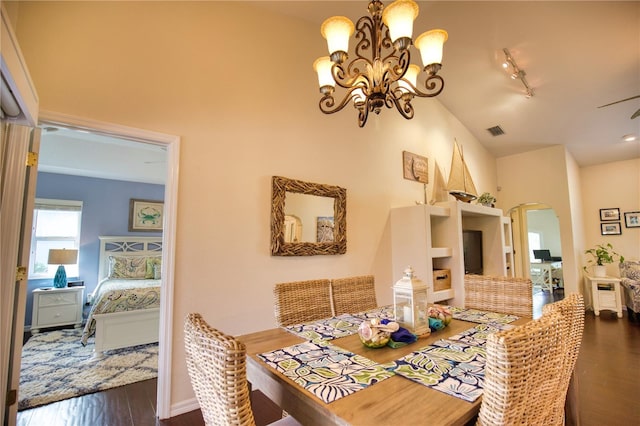 dining space featuring dark wood-type flooring, rail lighting, and a chandelier