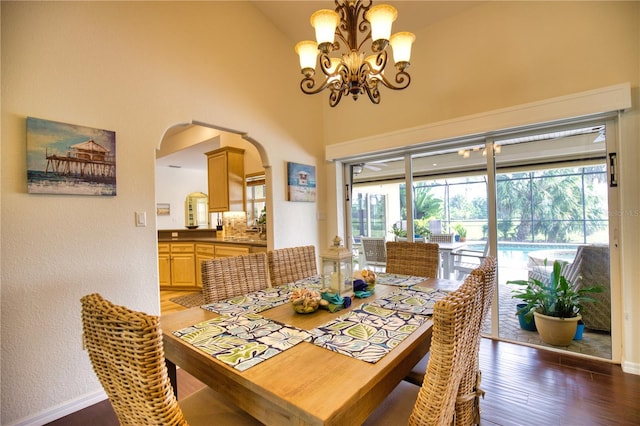 dining room featuring high vaulted ceiling, a chandelier, and dark wood-type flooring