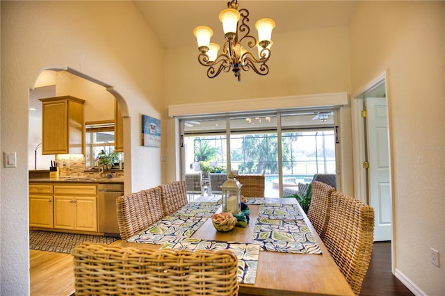 dining room with sink, hardwood / wood-style flooring, vaulted ceiling, and an inviting chandelier