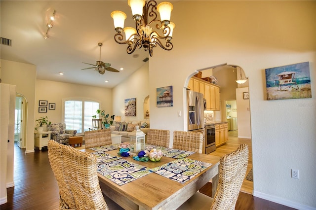 dining area with ceiling fan with notable chandelier, high vaulted ceiling, and dark hardwood / wood-style floors