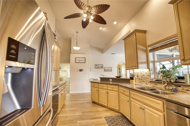 kitchen featuring lofted ceiling, decorative backsplash, sink, light hardwood / wood-style floors, and stainless steel appliances