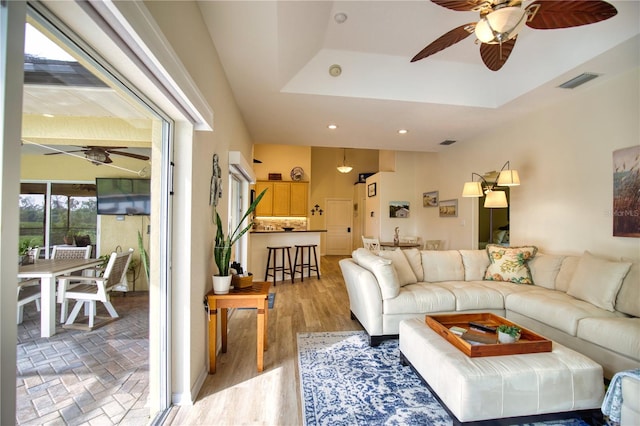 living room featuring hardwood / wood-style floors, a raised ceiling, and ceiling fan