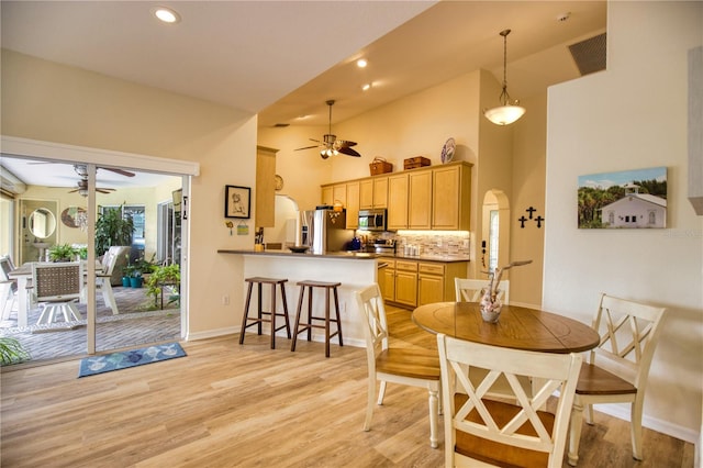 dining room featuring high vaulted ceiling, light hardwood / wood-style floors, and ceiling fan