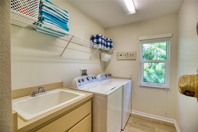 laundry room featuring sink, light hardwood / wood-style flooring, and washer and dryer