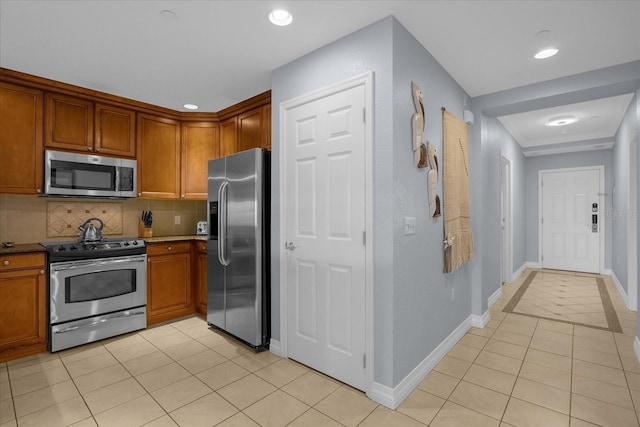 kitchen with tasteful backsplash, light tile patterned floors, and stainless steel appliances