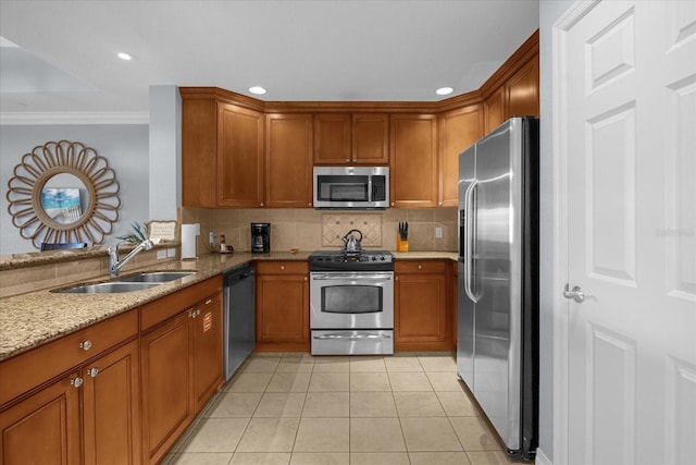 kitchen with sink, light tile patterned floors, ornamental molding, appliances with stainless steel finishes, and light stone counters