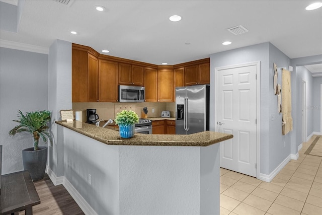 kitchen featuring decorative backsplash, crown molding, kitchen peninsula, and stainless steel appliances