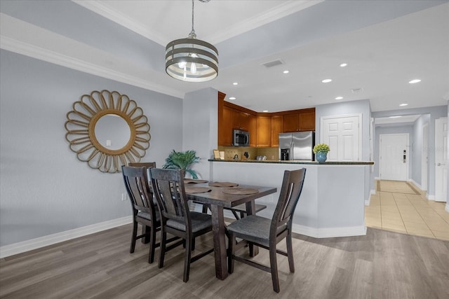 dining room with light hardwood / wood-style floors, crown molding, and an inviting chandelier