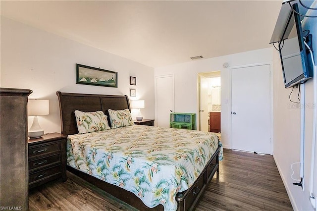 bedroom featuring ensuite bathroom and dark hardwood / wood-style flooring