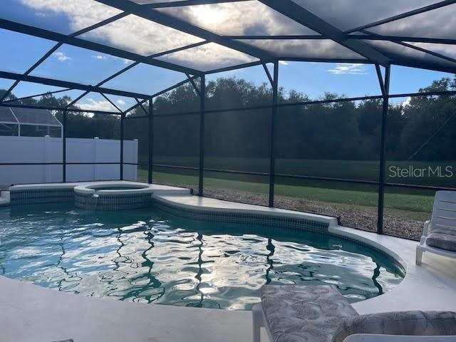 view of pool with glass enclosure and an in ground hot tub