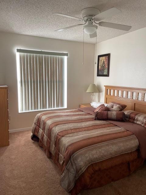 bedroom featuring a textured ceiling, carpet floors, and ceiling fan