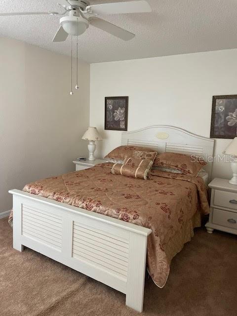 carpeted bedroom featuring a textured ceiling and ceiling fan