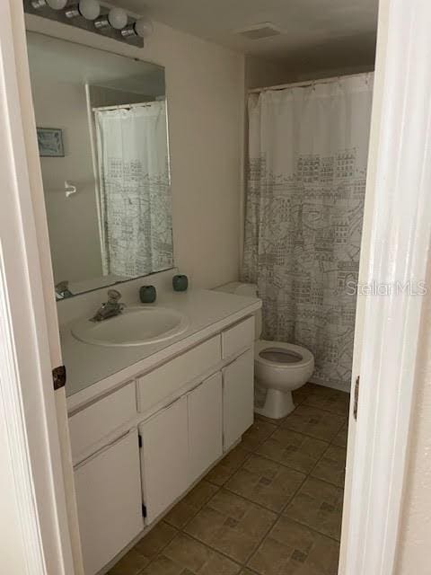 bathroom with toilet, vanity, and tile patterned floors