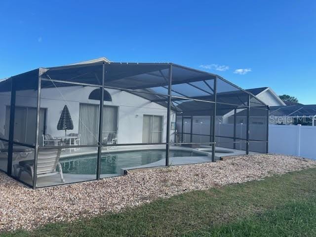 back of property featuring a lanai, a fenced in pool, and a patio area