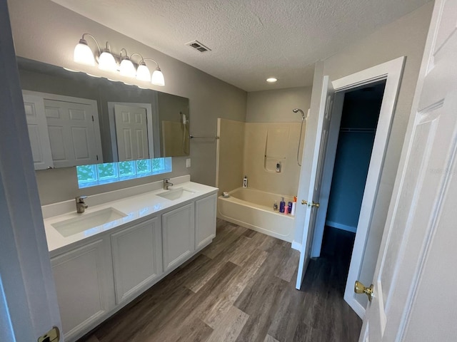 bathroom with shower / bathing tub combination, vanity, wood-type flooring, and a textured ceiling