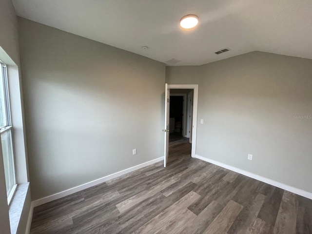 unfurnished room featuring dark hardwood / wood-style floors and lofted ceiling