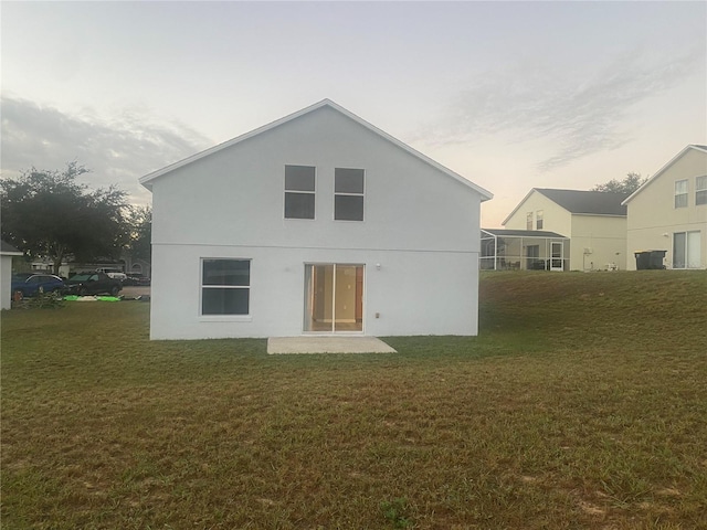 back house at dusk with a lawn