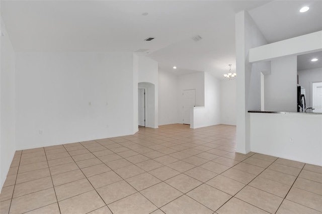 spare room featuring a notable chandelier, light tile patterned floors, and vaulted ceiling