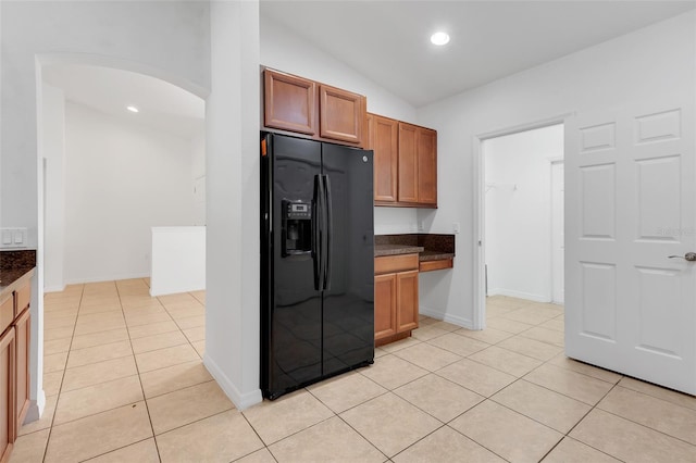 kitchen with black fridge, vaulted ceiling, and light tile patterned floors