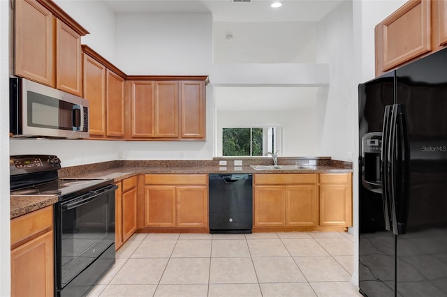 kitchen featuring light tile patterned floors, dark stone counters, sink, and black appliances