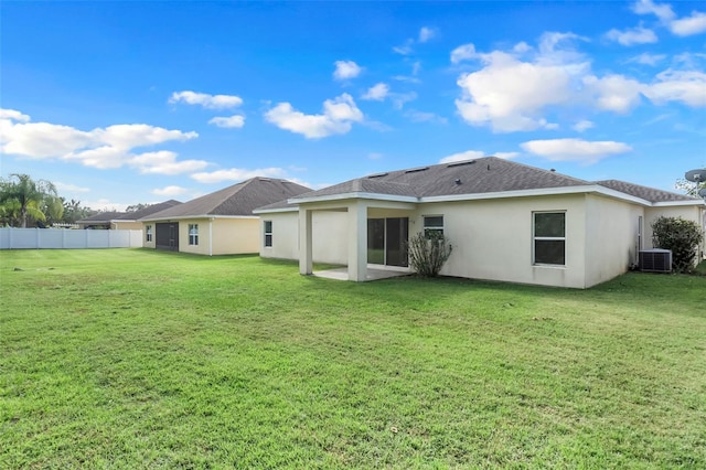 back of property with central AC and a yard