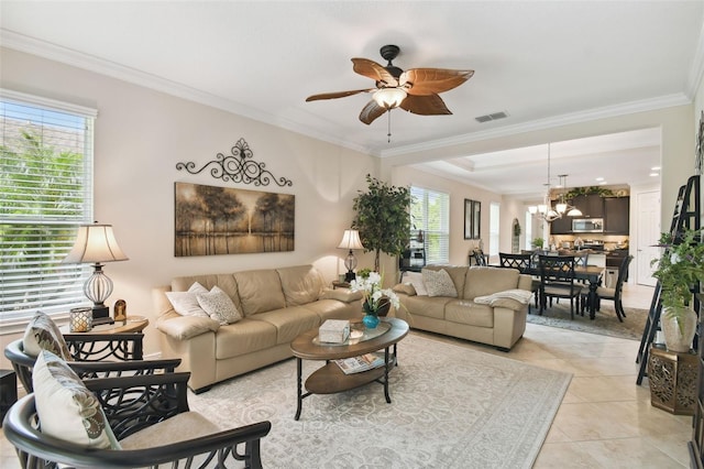 living room featuring ceiling fan with notable chandelier, light tile patterned floors, crown molding, and plenty of natural light