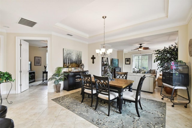 tiled dining room featuring ornamental molding, ceiling fan with notable chandelier, and a tray ceiling