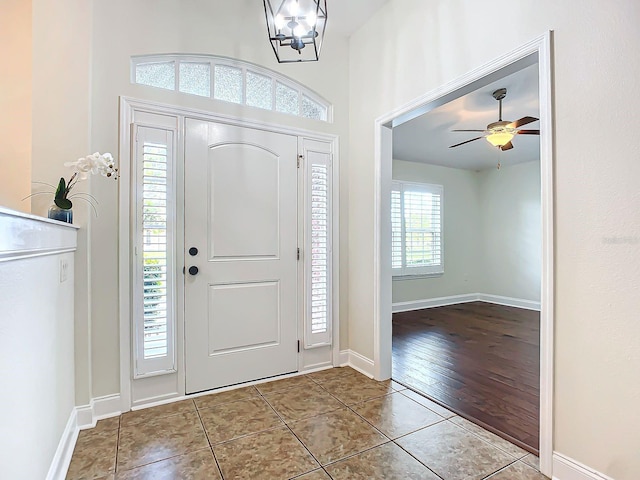 foyer entrance with ceiling fan with notable chandelier and light tile patterned floors