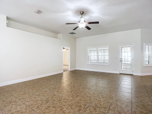 spare room with ceiling fan and dark tile patterned floors