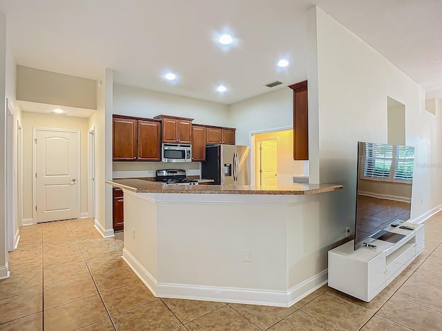 kitchen with light tile patterned floors, kitchen peninsula, and appliances with stainless steel finishes