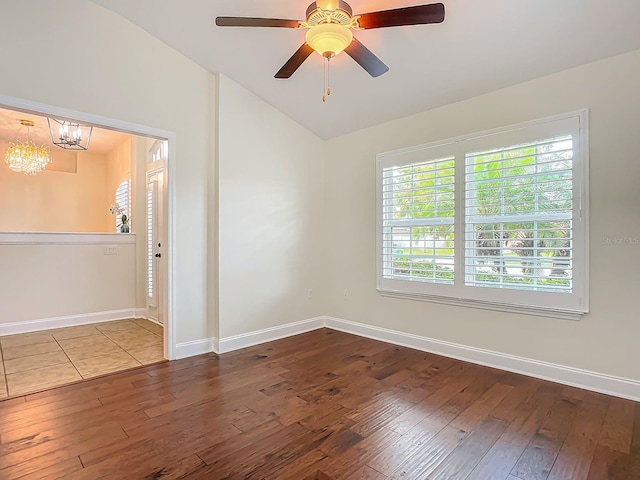 spare room with hardwood / wood-style flooring, lofted ceiling, and ceiling fan with notable chandelier