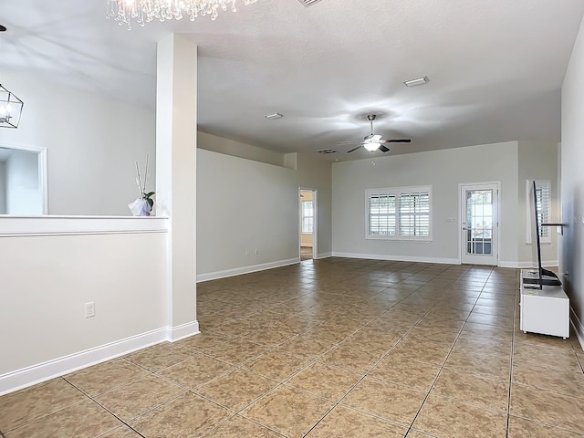 spare room with tile patterned flooring, ceiling fan with notable chandelier, and a textured ceiling