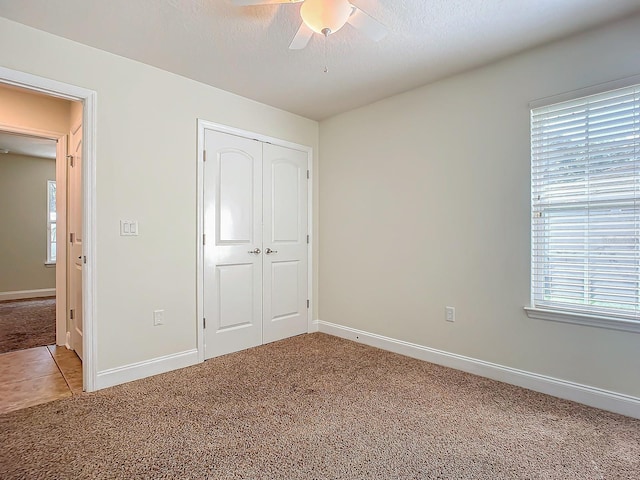 unfurnished bedroom featuring ceiling fan, carpet flooring, a textured ceiling, and a closet