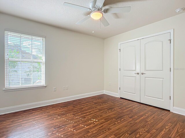 unfurnished bedroom featuring ceiling fan, dark hardwood / wood-style floors, a closet, and a textured ceiling