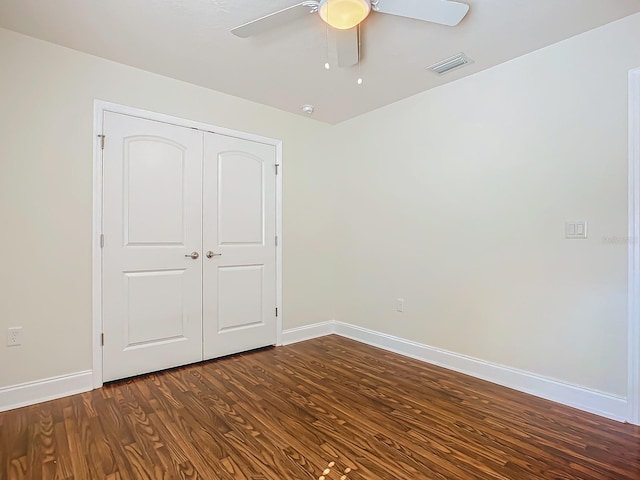 unfurnished bedroom with dark wood-type flooring, a closet, and ceiling fan